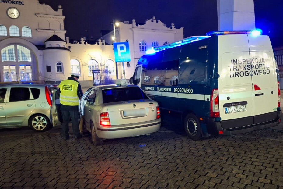 Inspektor Transportu Drogowego przeprowadza kontrolę taksówki na tle budynku dworca kolejowego