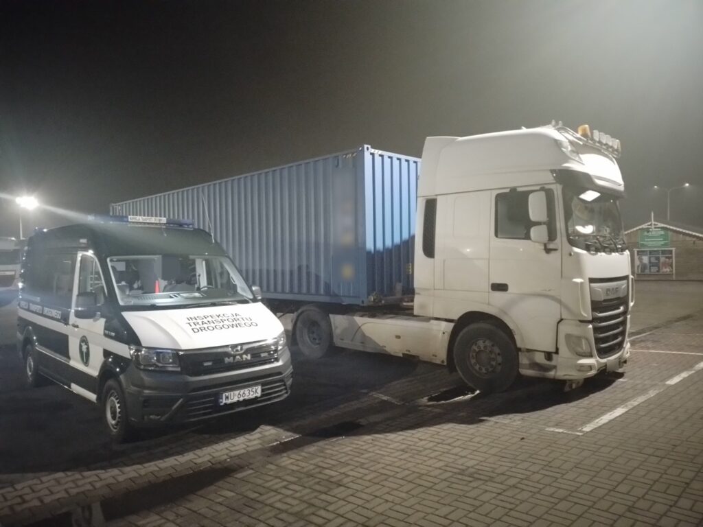 Kontrola drogowa ciężarówki przez Inspekcję Transportu Drogowego na parkingu nocą