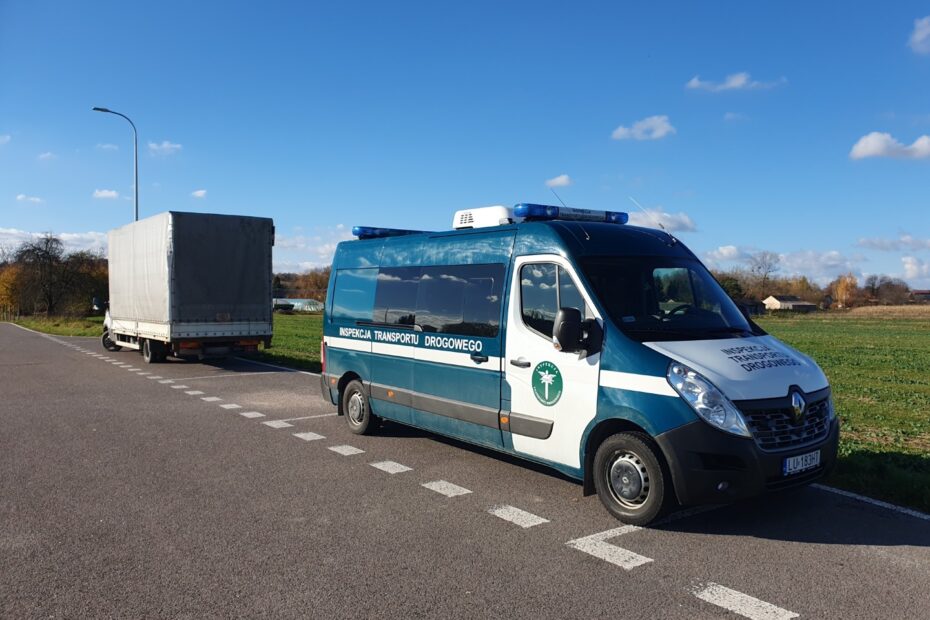 Pojazd Inspekcji Transportu Drogowego zatrzymał dostawczy samochód na poboczu drogi w słoneczny dzień.