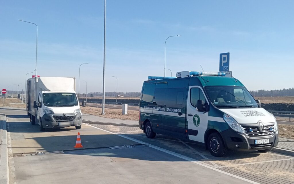 Pojazd Inspekcji Transportu Drogowego zatrzymał dostawczy samochód do kontroli na punkcie wagowym przy drodze.