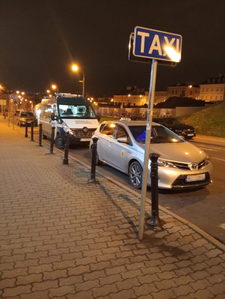 Pojazd Inspekcji Transportu Drogowego i taksówka zatrzymane na postoju TAXI nocą.