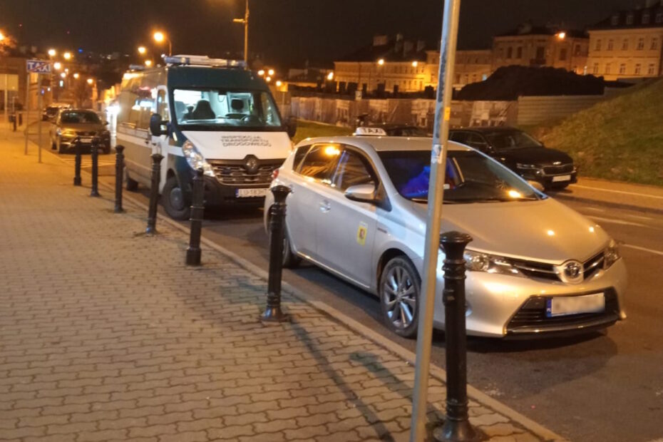 Pojazd Inspekcji Transportu Drogowego i taksówka zatrzymane na postoju TAXI nocą.