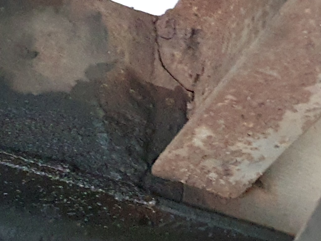 Pęknięty i skorodowany element stalowej konstrukcji ramy pojazdu – widok z dołu.