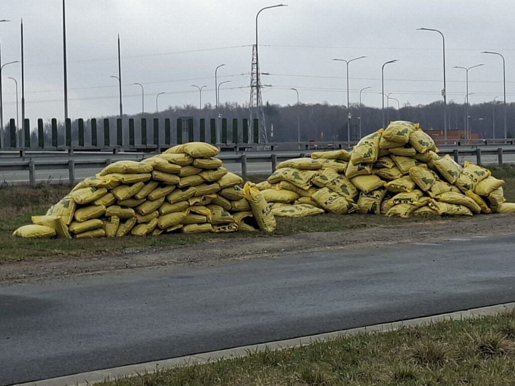 Stosy żółtych worków z ładunkiem ułożone przy poboczu drogi ekspresowej