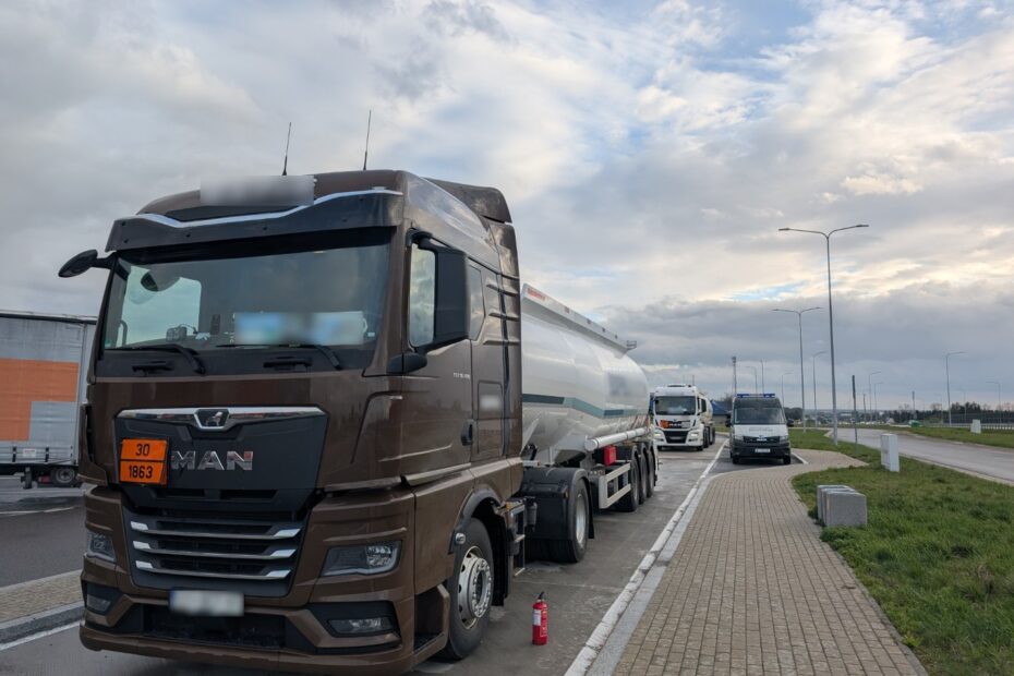 Ciągnik siodłowy z cysterną przewożącą materiały niebezpieczne zatrzymany do kontroli drogowej, w tle pojazd służb kontrolnych