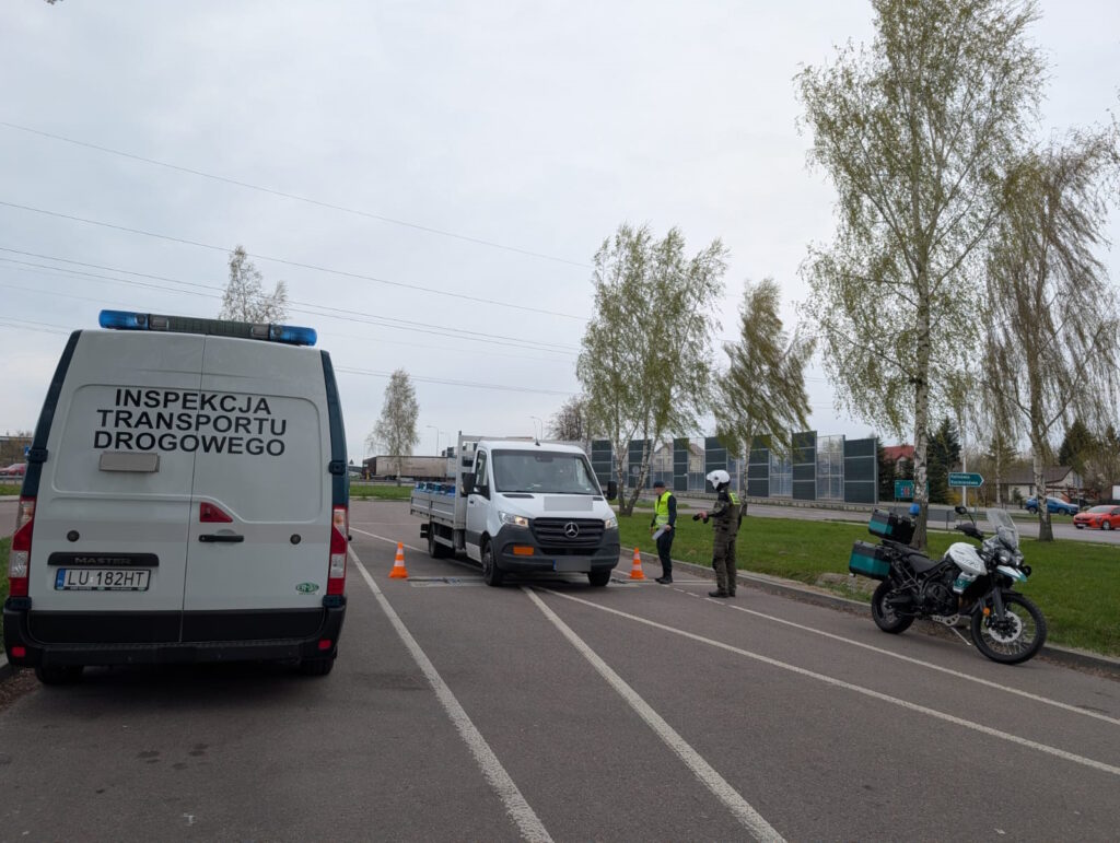 Kontrola drogowa pojazdu dostawczego – inspektorzy ITD i funkcjonariusz na motocyklu sprawdzają dokumenty